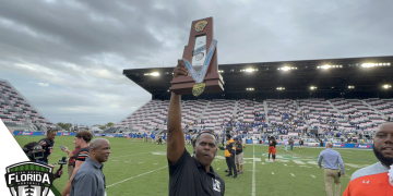 Lake Wales head coach Tavaris Johnson holds up the state championship trophy, the first to be won by the Highlanders' football program on Friday, December 16, 2022 at DRV PNK Stadium in Fort Lauderdale, Fla. [Joshua Wilson/FloridaHSFootball.com}